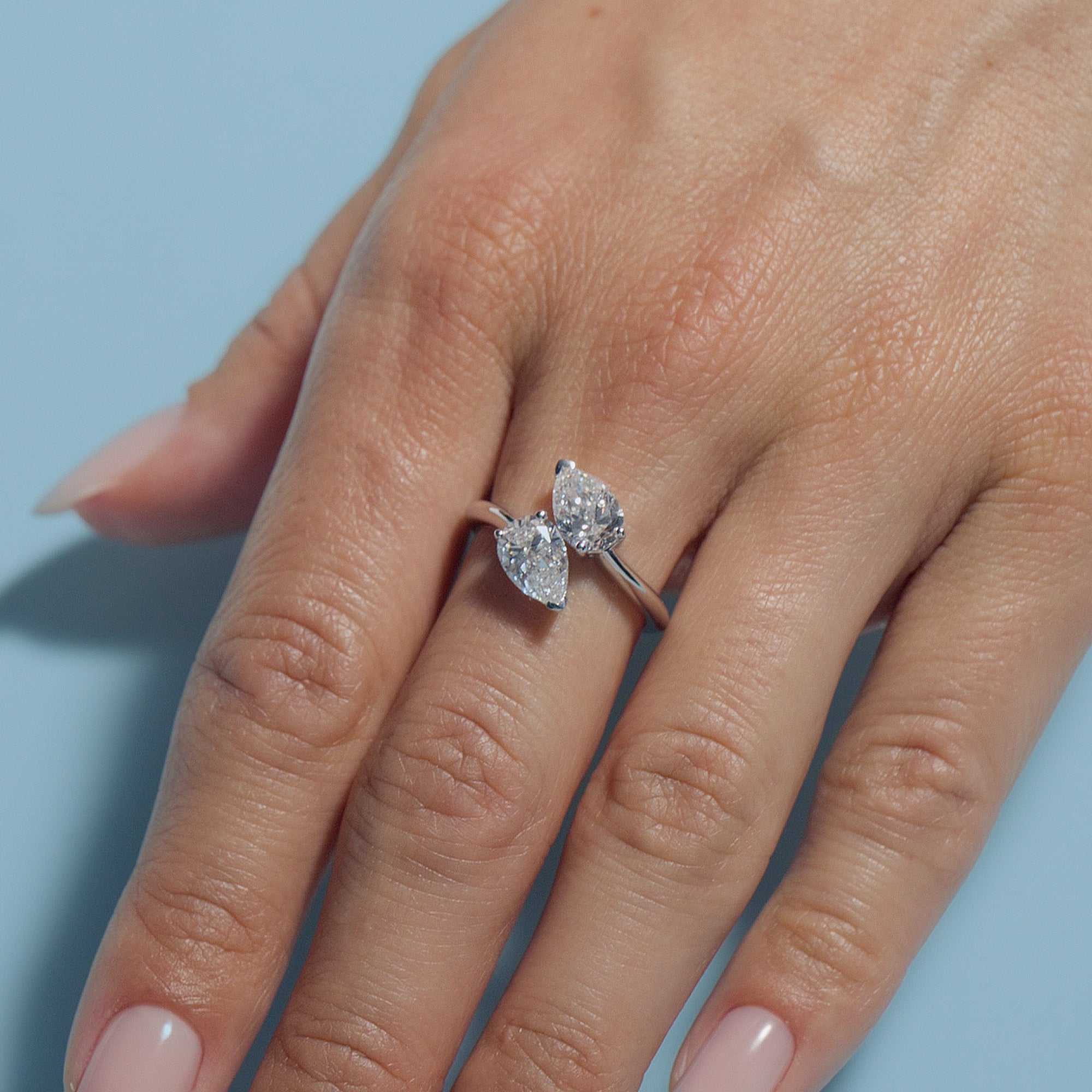 Pear Lab Diamonds Toi & Moi Ring on a hand against a light blue background