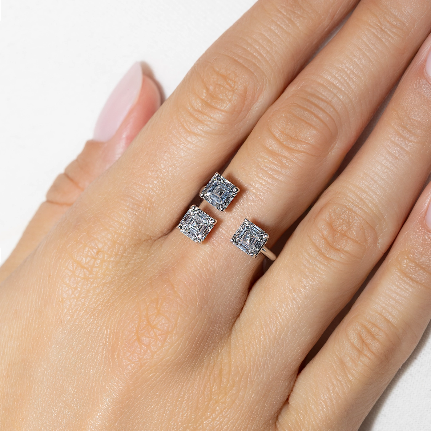 Open ring with three asscher-cut diamonds in white gold worn on finger