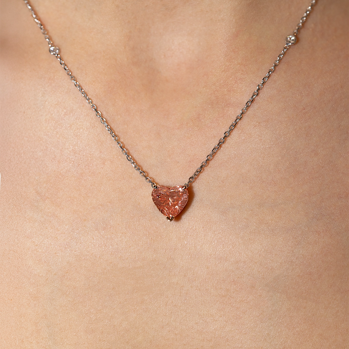 Heart-shaped pink lab-grown diamond pendant necklace in rose gold with sautoir white gold chain, worn on the neck.