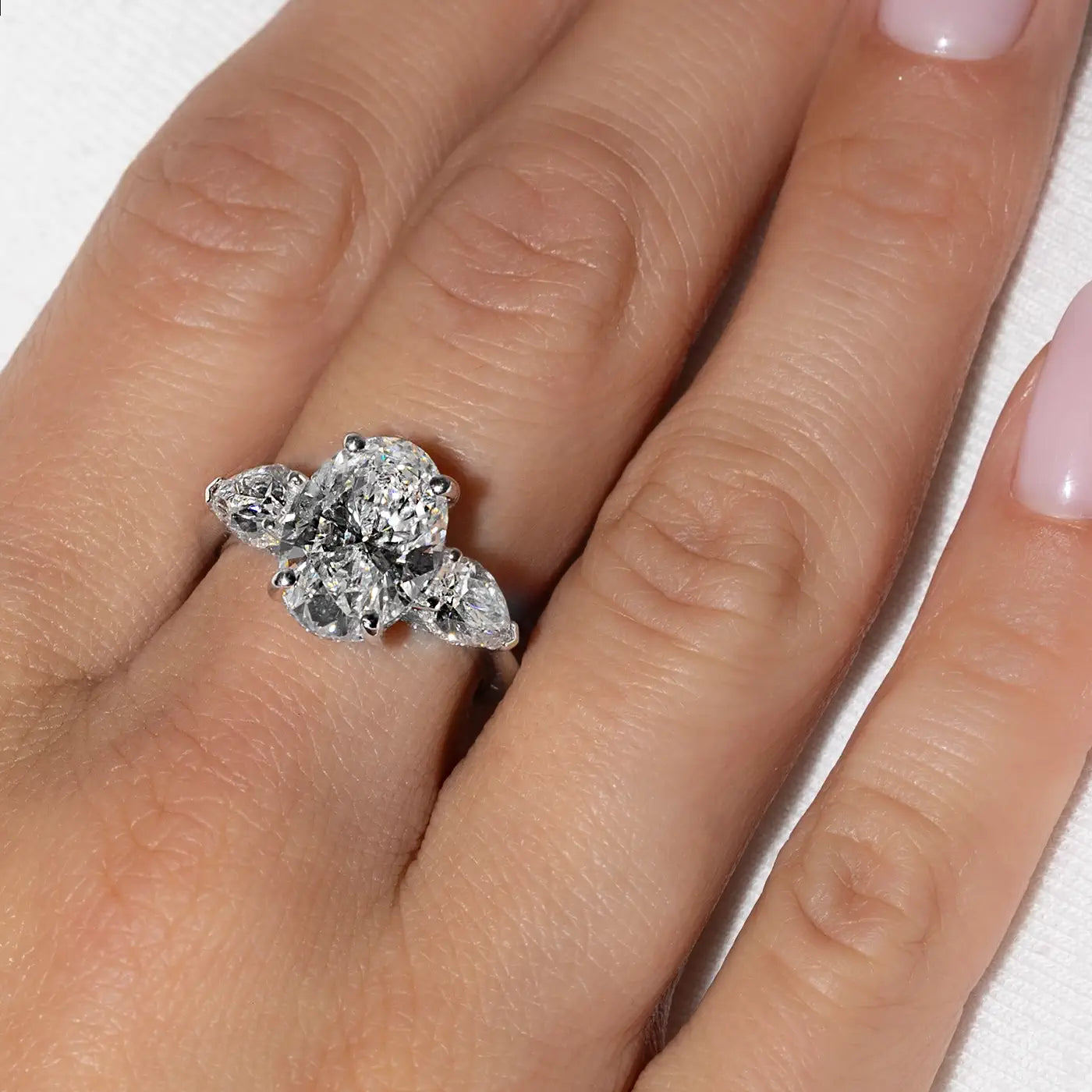 A 18k white gold ring composed of Oval-shaped center stone and pear trilogy