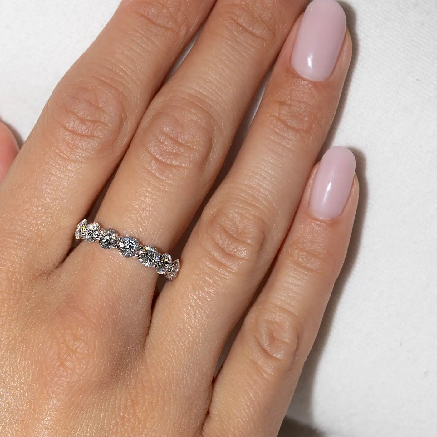 18k white gold eternity ring composed of round lab diamonds worn on hand by the model