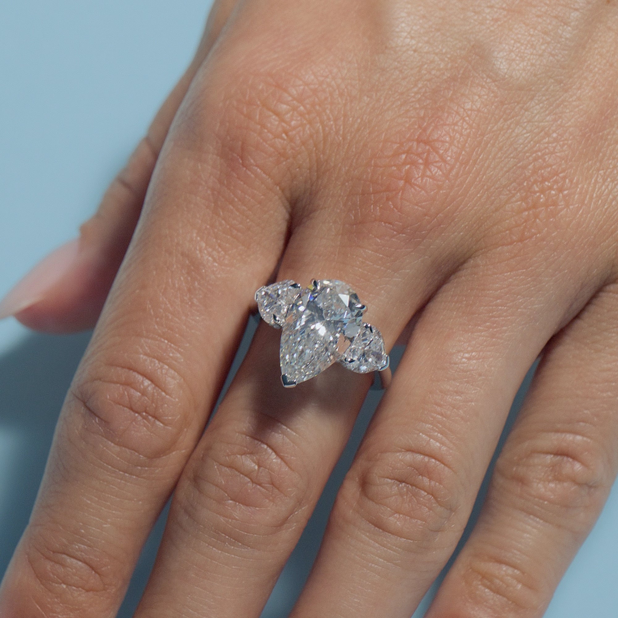 Pear Lab Diamond Heart Trilogy ring on a model's finger with a light blue background