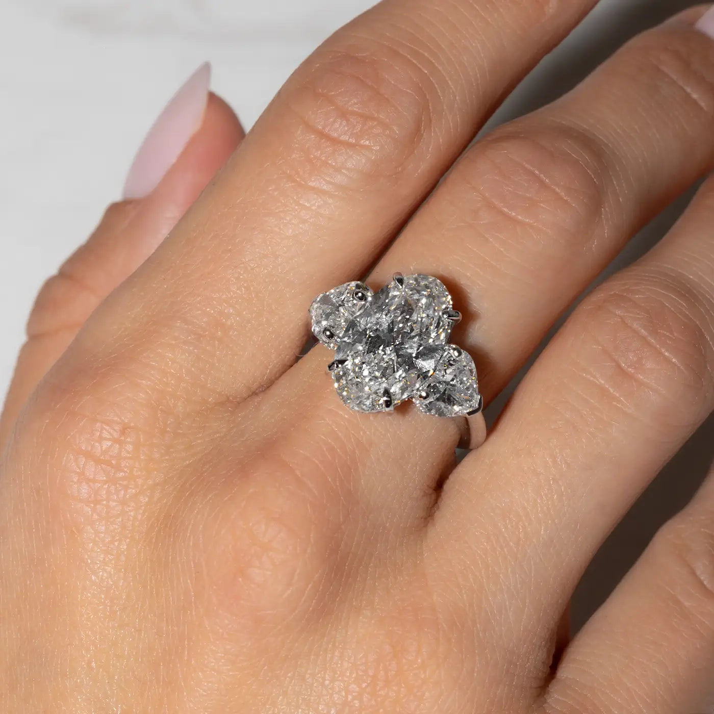 Oval-shaped center stone in heart trilogy, settings made in 18k white gold worn on hand