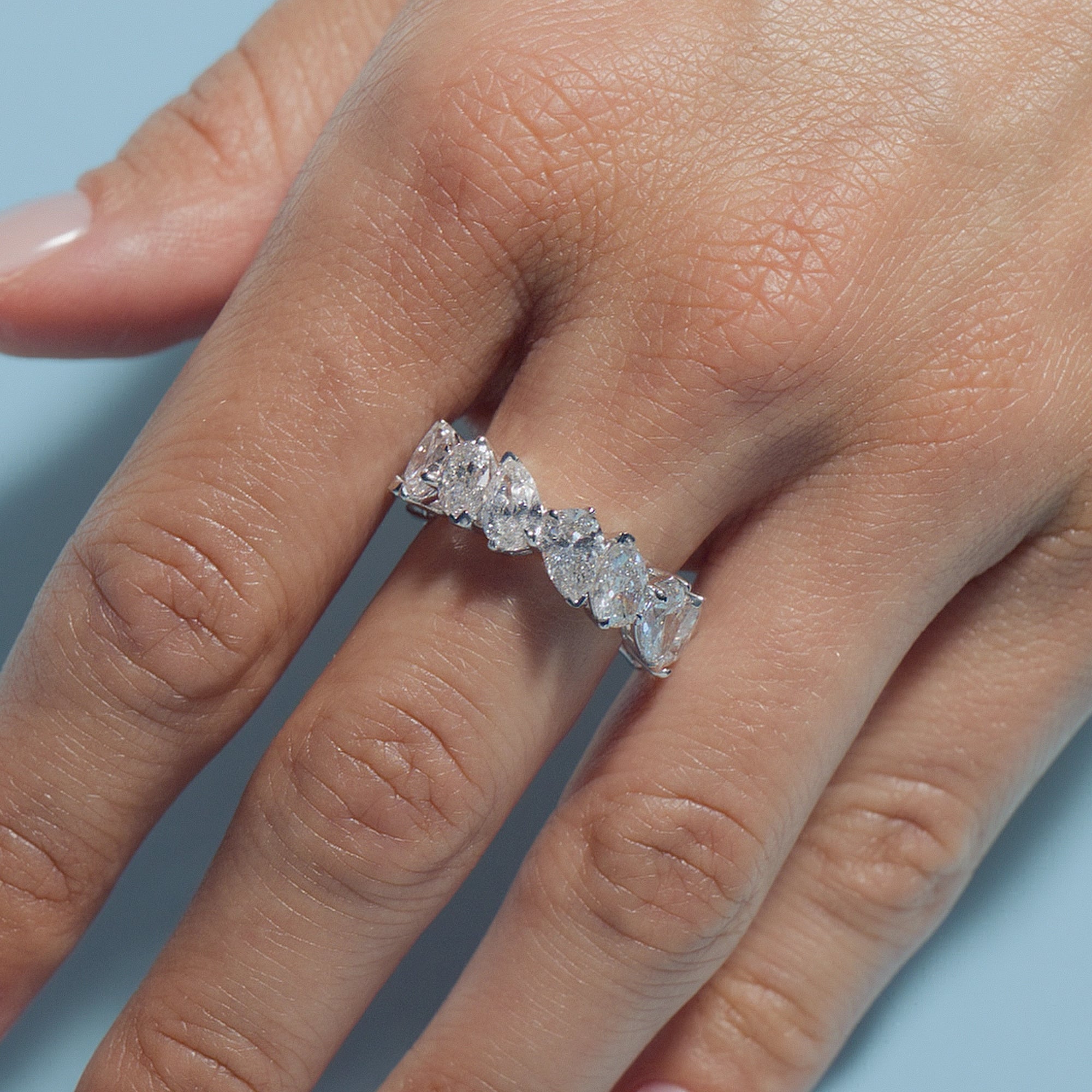 Pear Lab Diamonds Eternity Ring on a model's finger against a light blue background