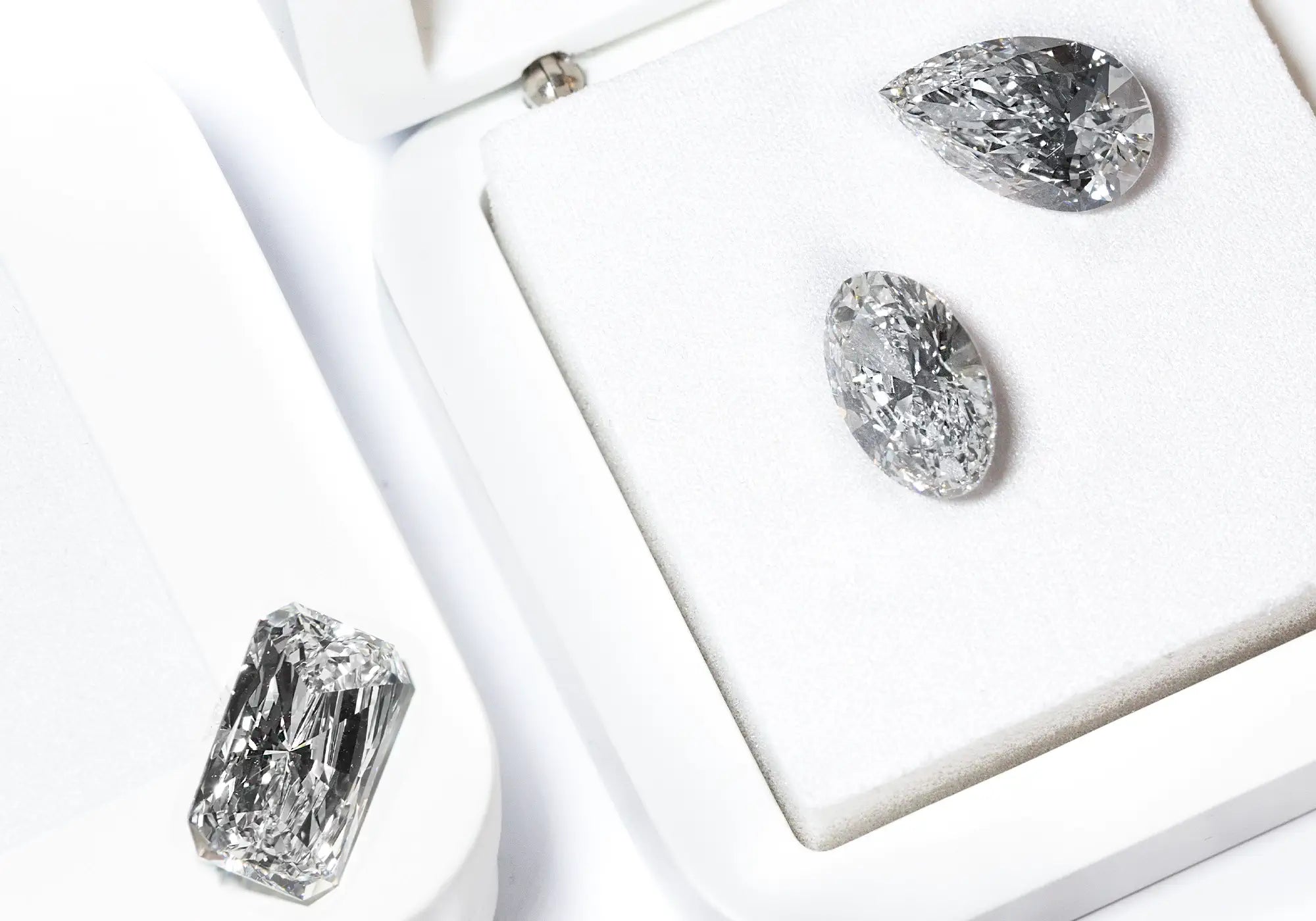 White Loose Lab-Grown Diamonds in different cuts on top a white jewelry box with sponge