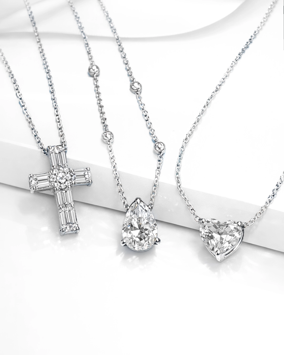 Luxury diamond necklaces in white gold with cross pendant, pear-shaped diamond with Sautoir, and heart-cut diamond charms