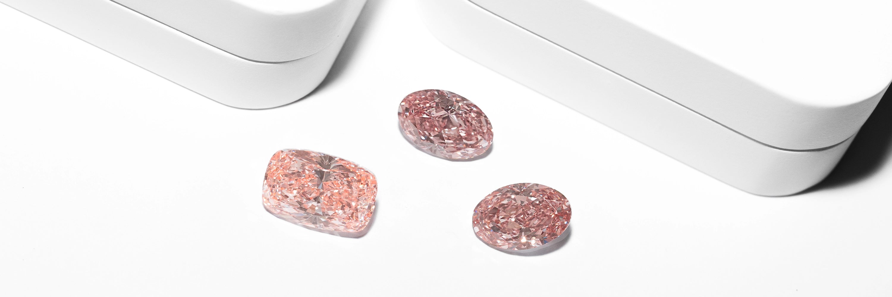 Fancy pink loose lab diamonds in oval and cushion cuts on white background