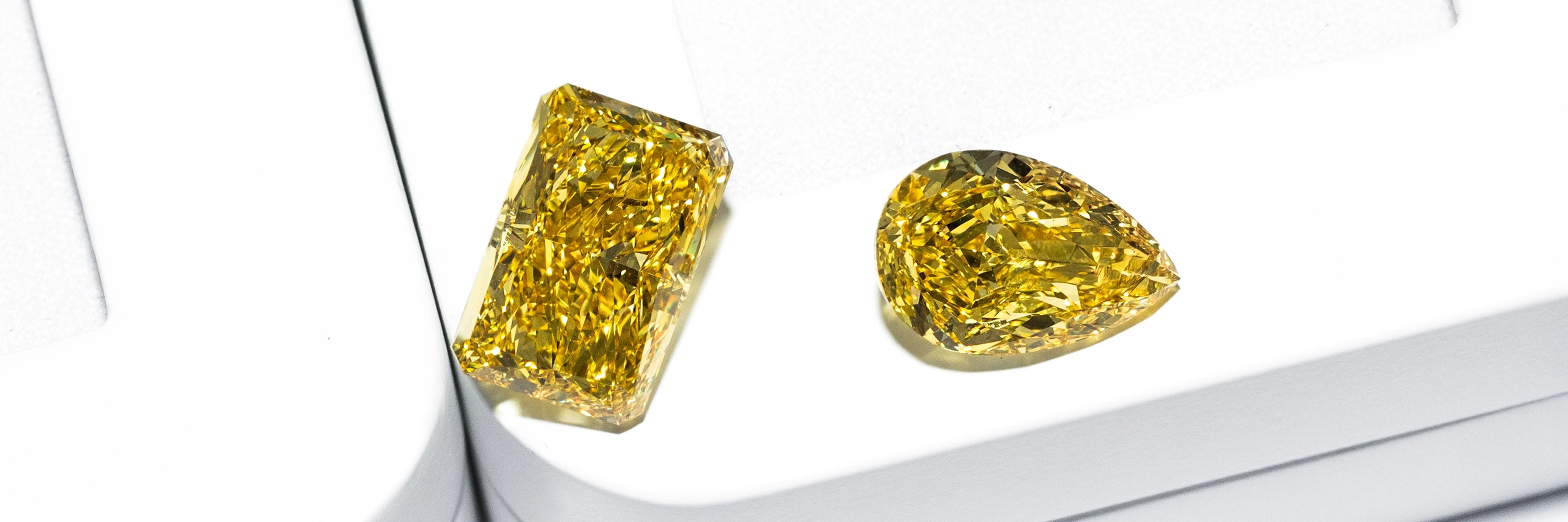 Fancy yellow loose lab diamonds in radiant and pear cuts on white background by BÄL Diamonds