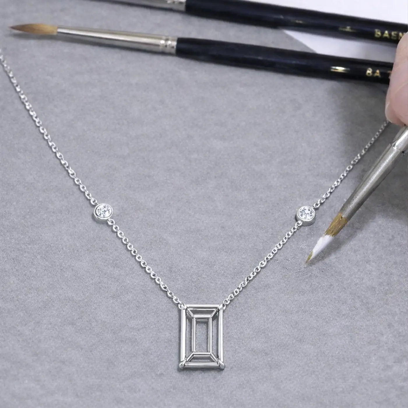 Emerald-cut diamond pendant necklace with Sautoir, photographed on a jeweler’s workbench
