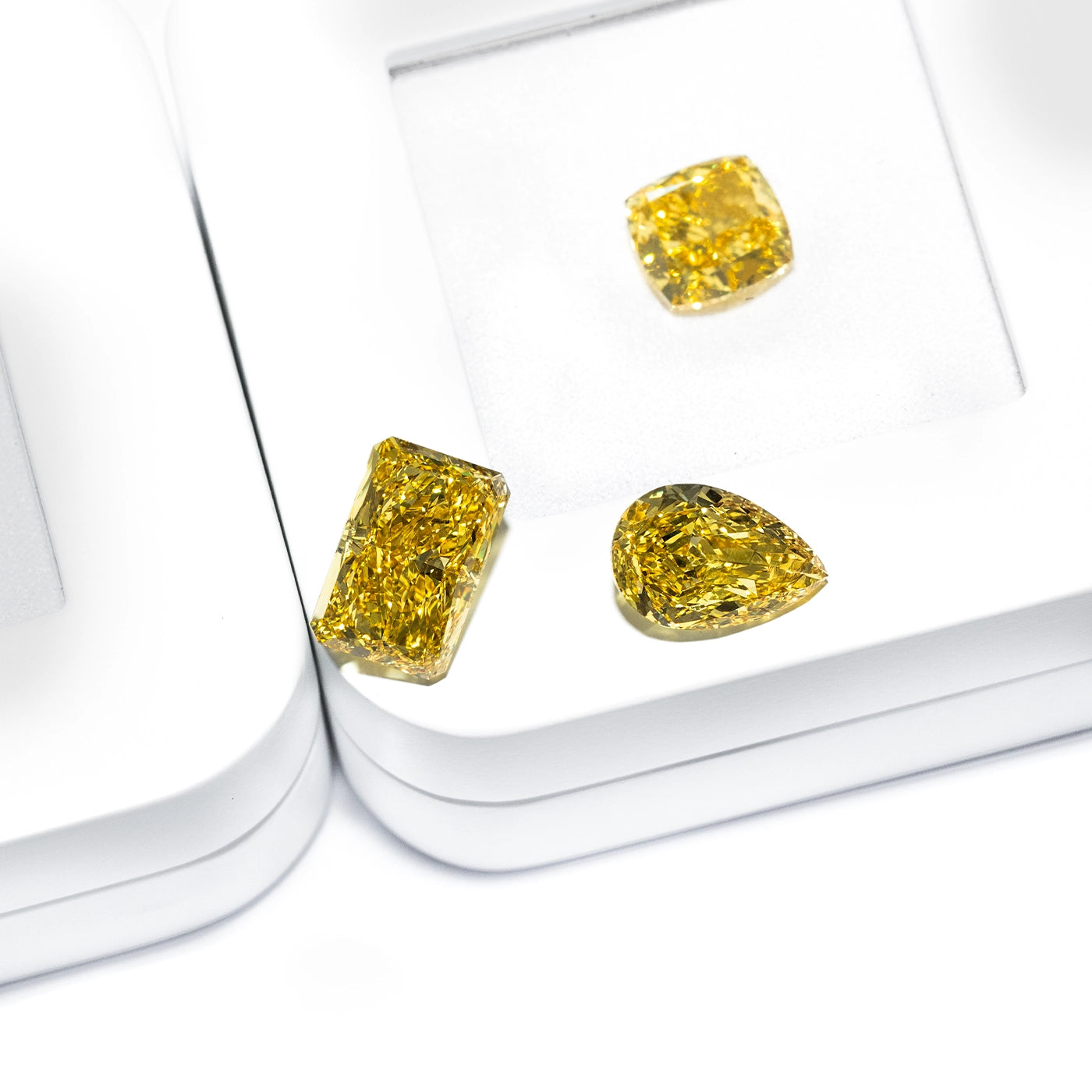 fancy yellow loose lab diamonds in radiant, cushion, and pear cuts displayed individually in a jewelry box