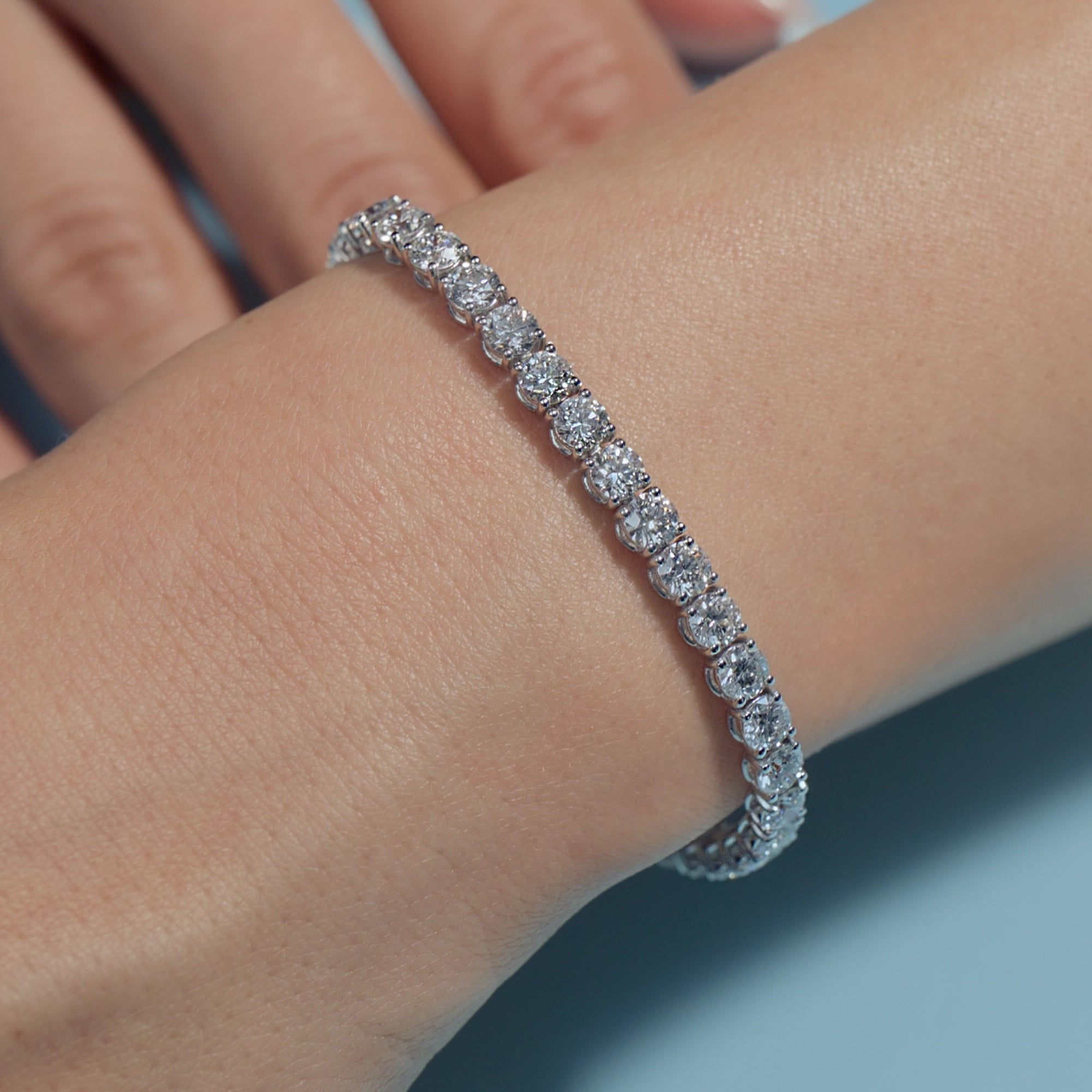 10.87ct Round Lab Diamonds Tennis Bracelet on the wrist of the model with light blue background 