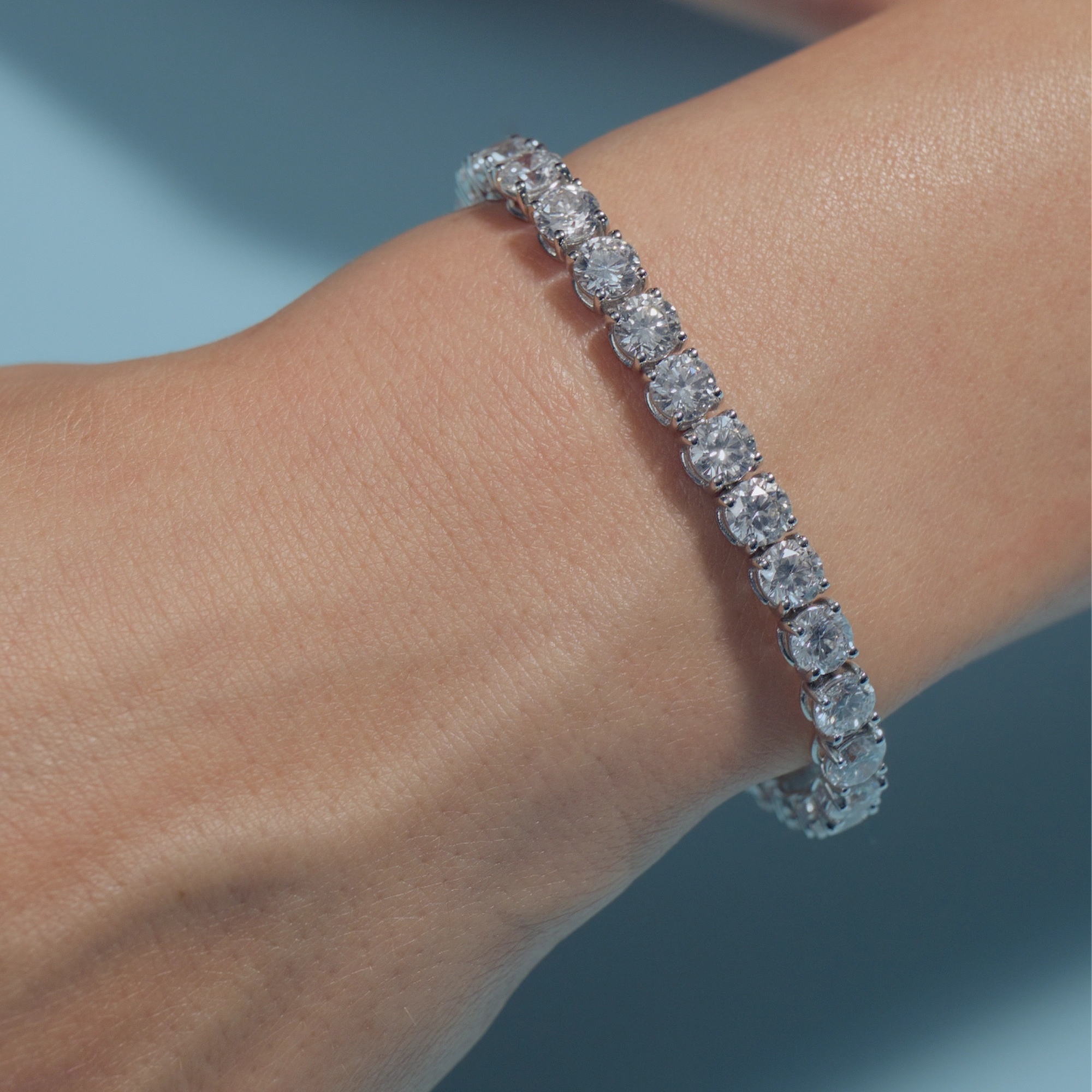 17.65ct Round Lab Diamonds Tennis Bracelet on the wrist of the model on a light blue background