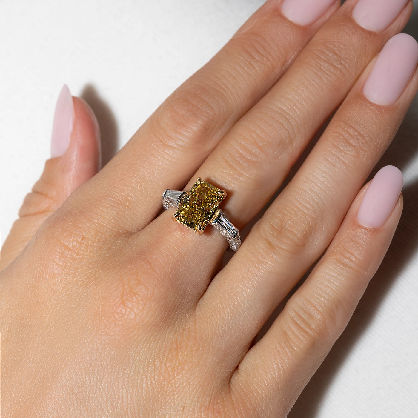 Radiant Fancy Vivid Yellow Lab Diamond with tapers as side stones worn on the hands of the model 