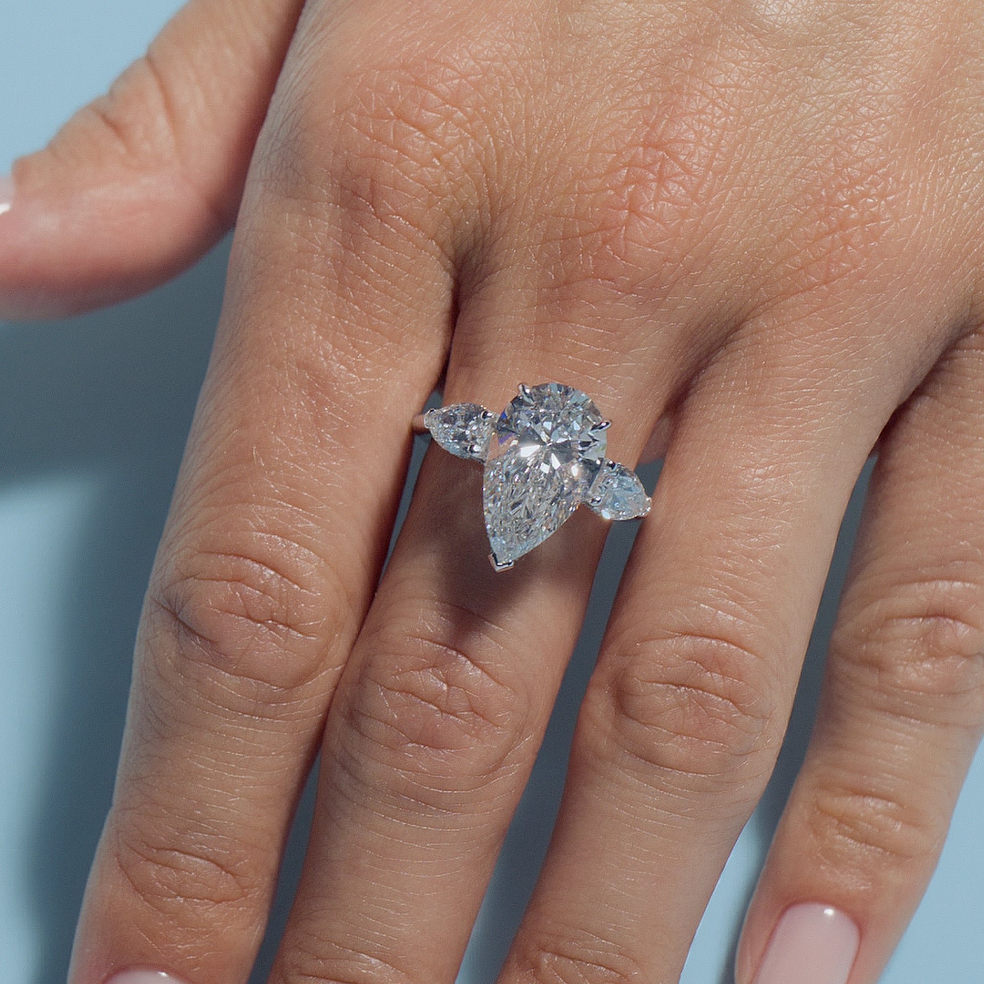 Pear Lab Diamond Pear Trilogy ring on a hand with a light blue background