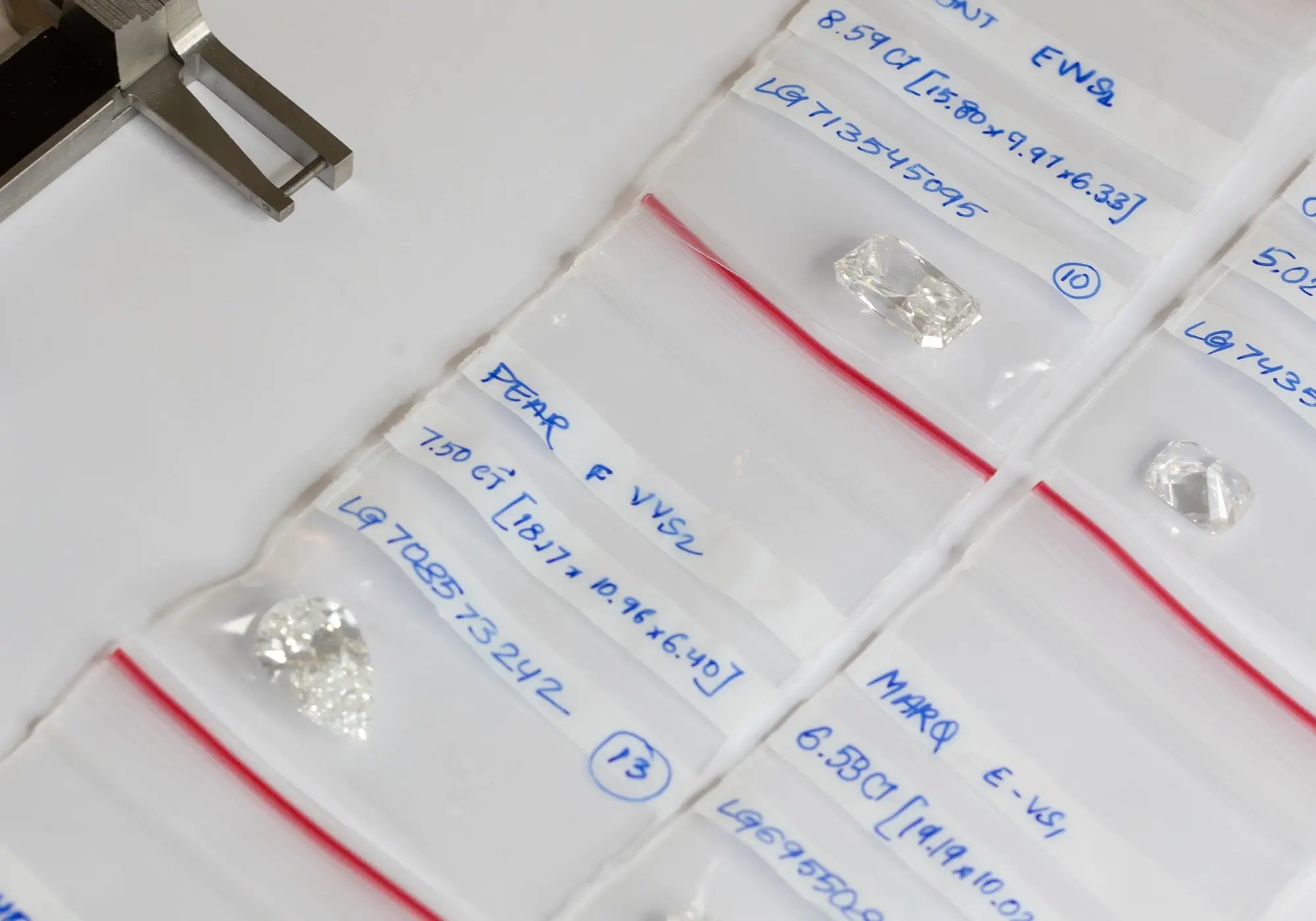 Different cuts of white lab diamonds on top of a small pouches with description of every stones