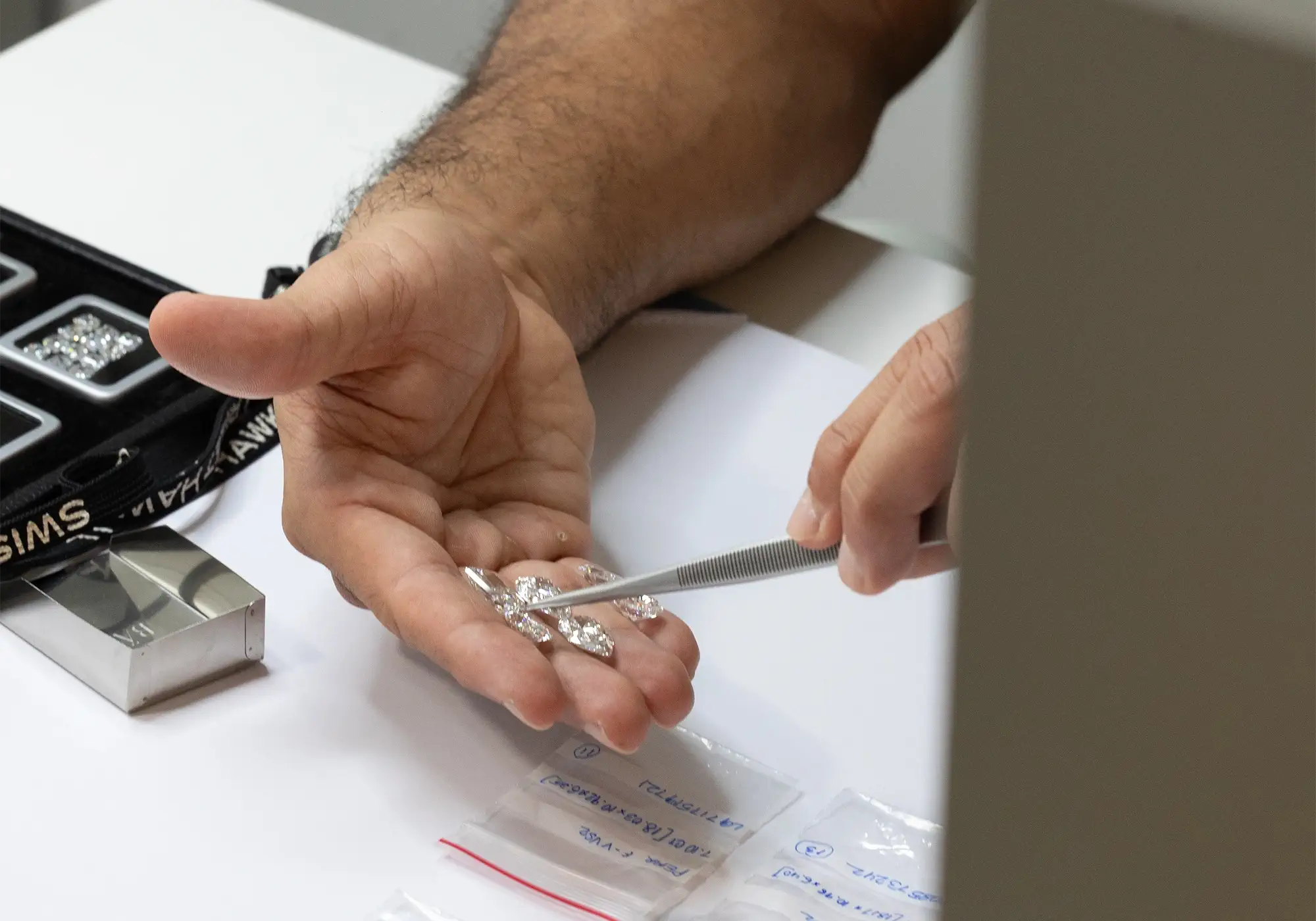 Jeweler inspecting loose lab diamonds with tweezers at a jewelry workshop