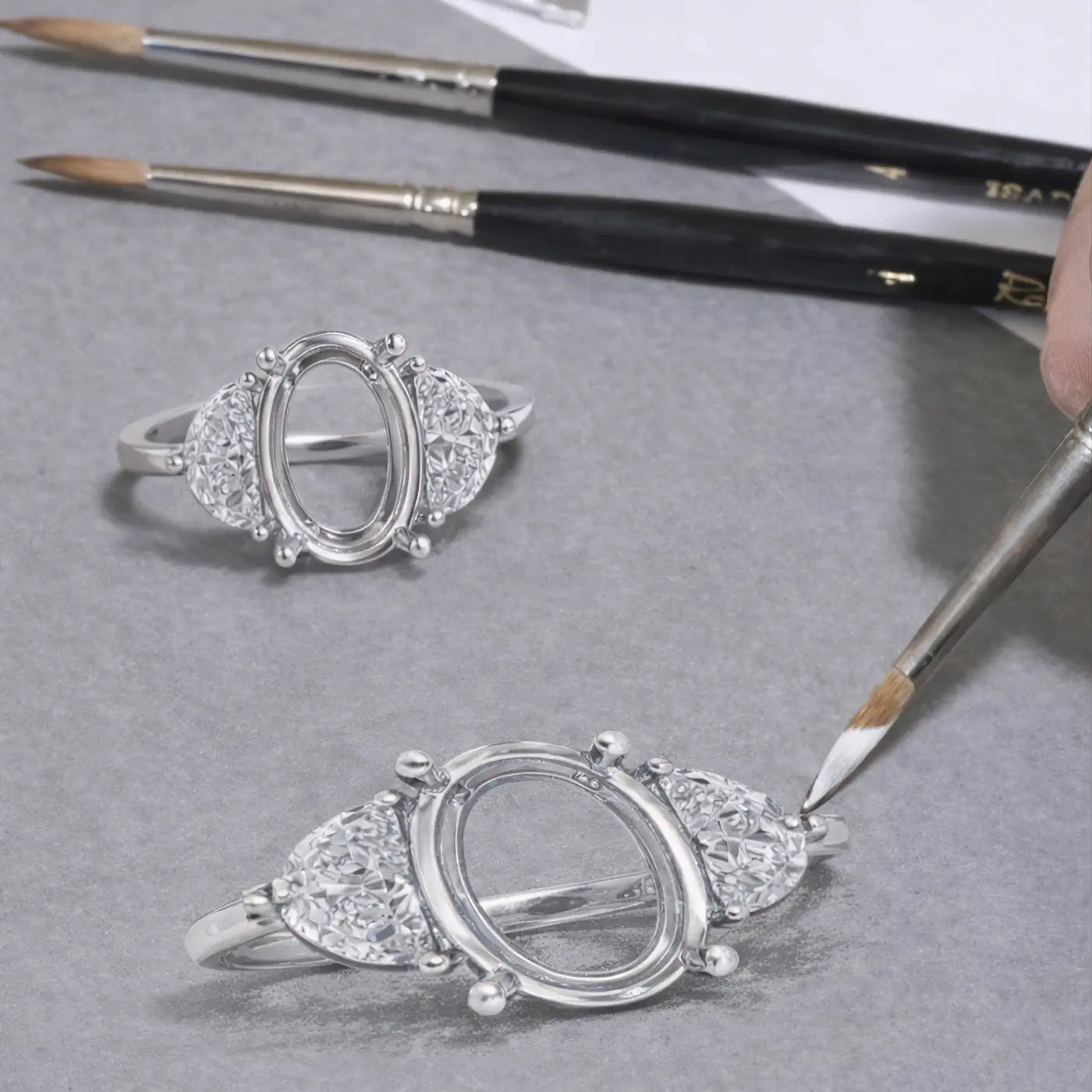 Oval diamond ring setting with side stones carefully finished by hand on a jeweler’s workbench