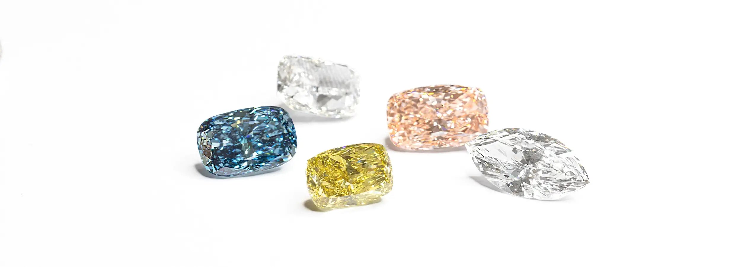Image of Different cuts and colors of lab-grown diamonds on a white surface