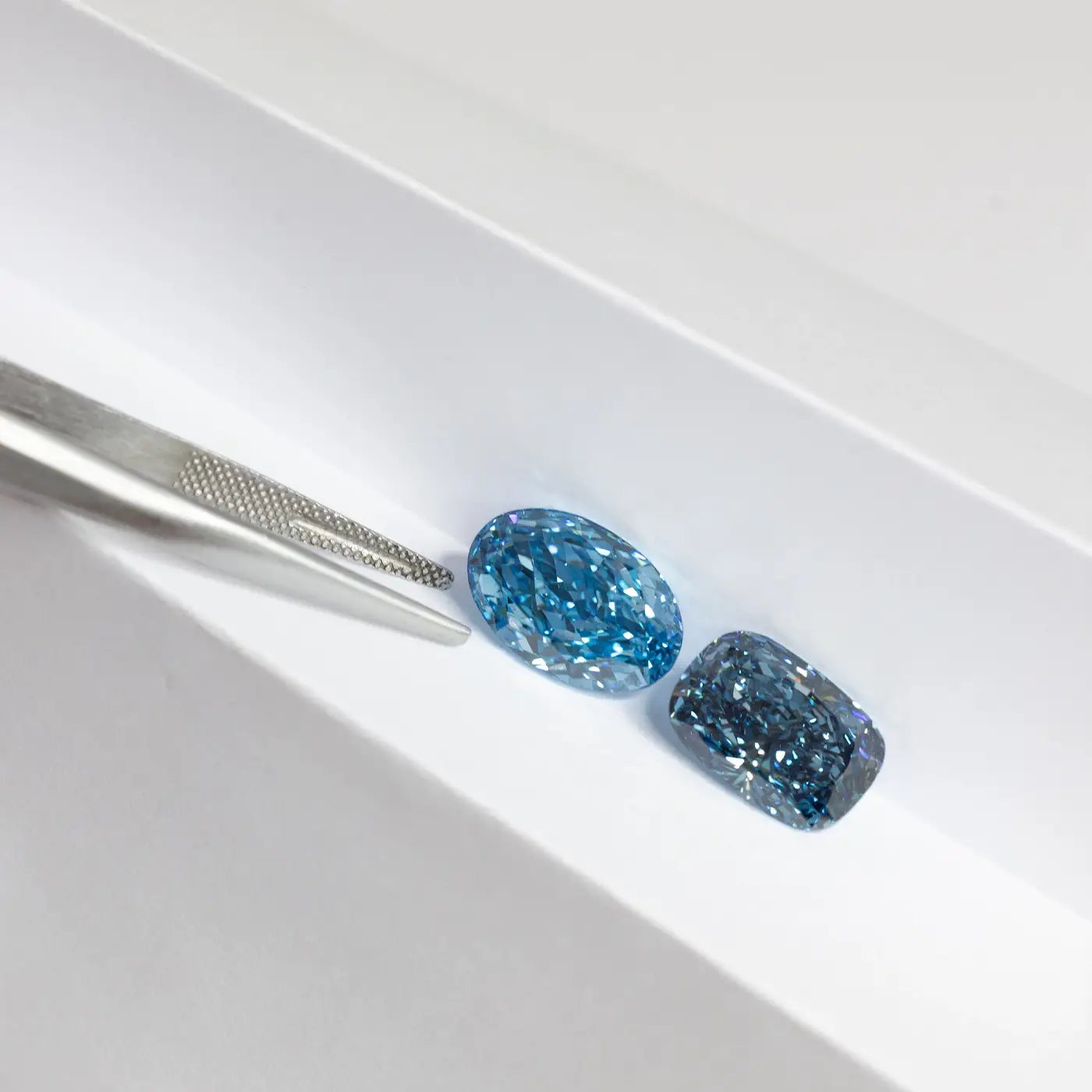 Fancy Blue Loose Diamonds on top of a bond paper with tweezer 
