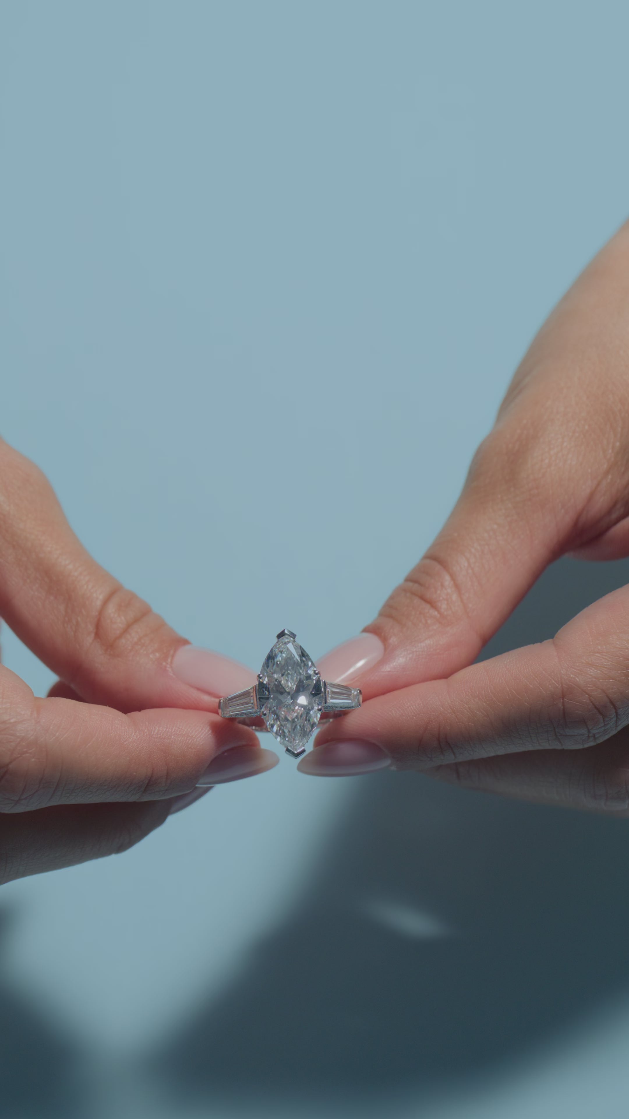 A video of a 6.53ct Marquise Lab Diamond Intricate Trilogy Ring presented by the model of BAL Diamonds on a light blue background