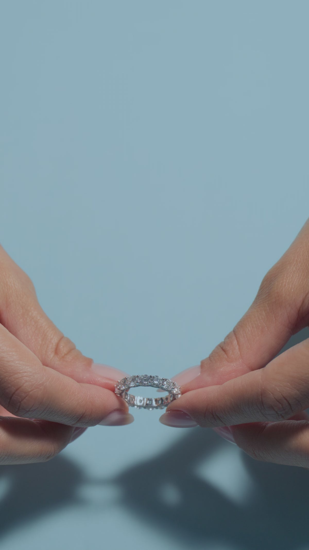 A short clip of a 4.68ct Round Lab Diamonds Intricate Eternity Ring presented by the model of BAL Diamonds on a light blue background 