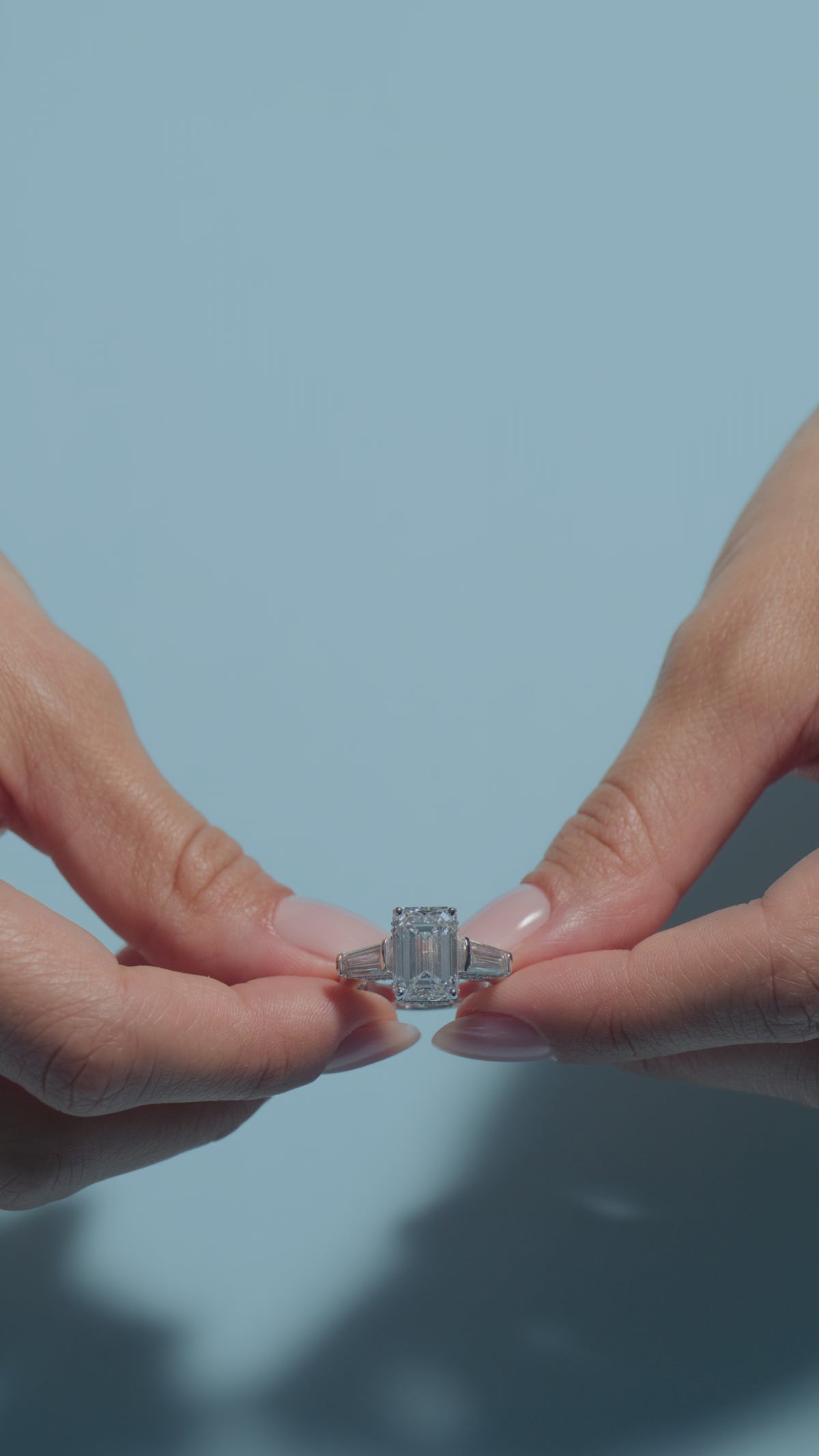 A video presenting a 5.01ct Emerald Lab Diamond Intricate Trilogy Ring held and worn by the model of BAL Diamonds on a light blue background