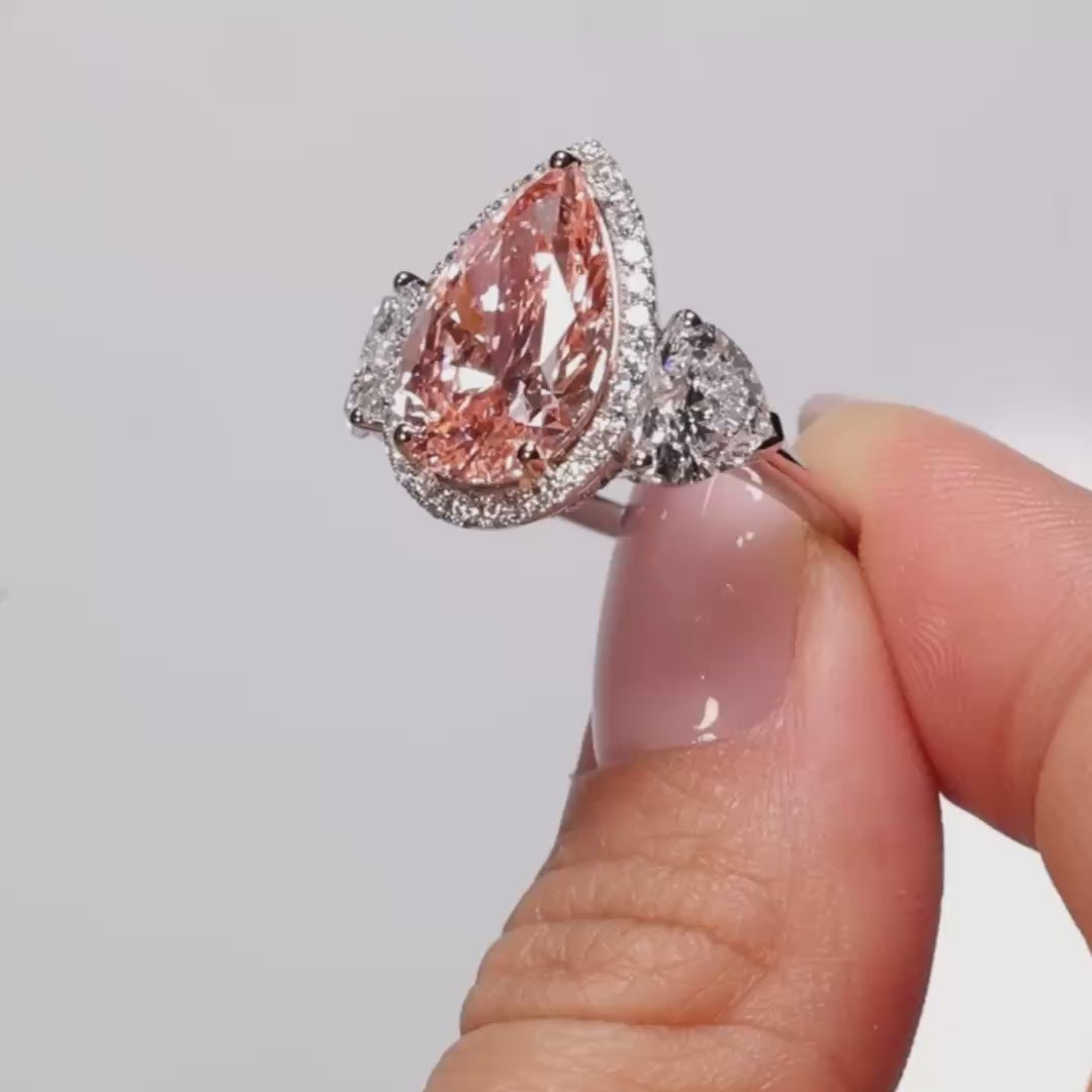 A video clip of a Pear Fancy Vivid Pink Lab Diamond Heart Trilogy held by the model 