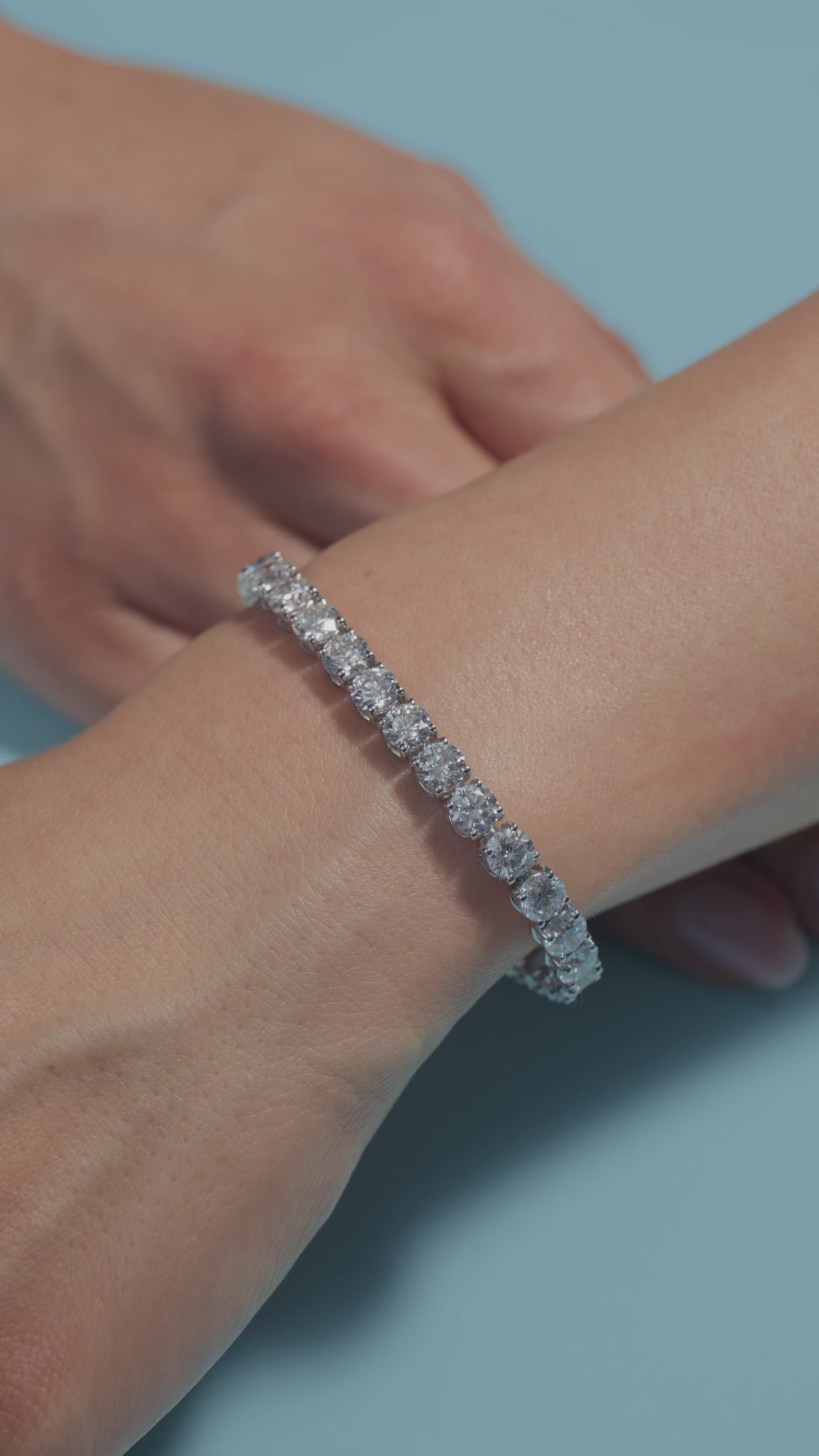 A video presenting a 17.65ct Round Lab Diamonds Tennis Bracelet worn on the wrist of the model on a light blue  background 