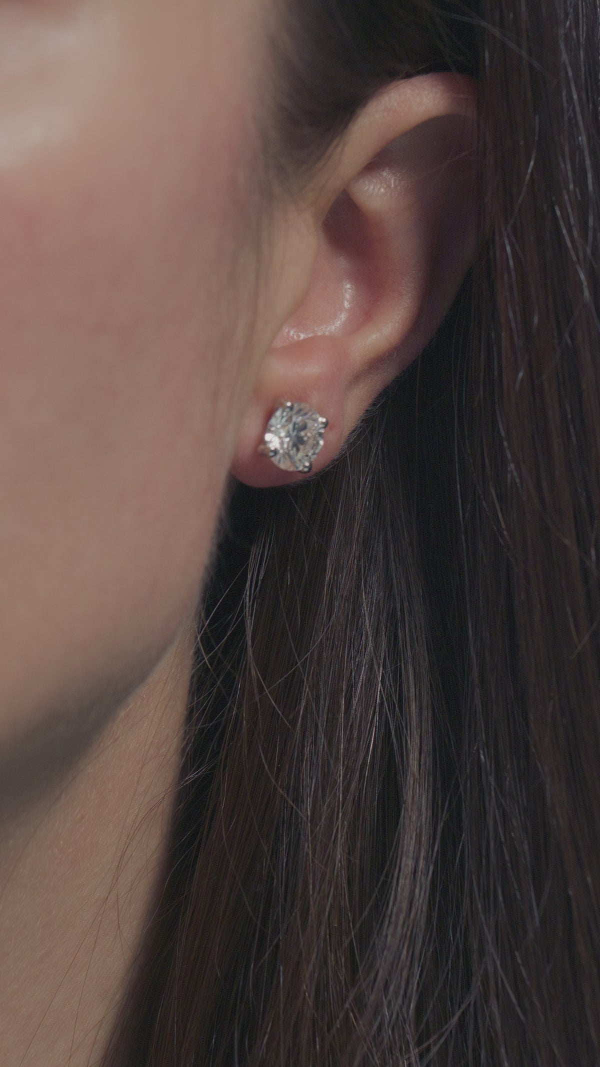 A short video presenting a 2ct Round Solitaire Earrings worn on the lobe of the model 