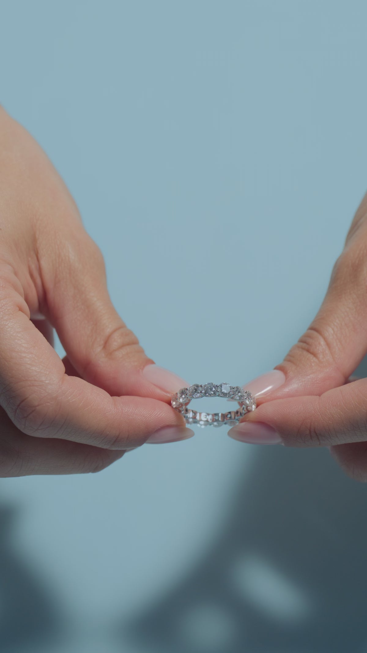 A video presenting a 4.1ct Round Lab Diamonds Eternity Ring held and worn by the model in a light blue background