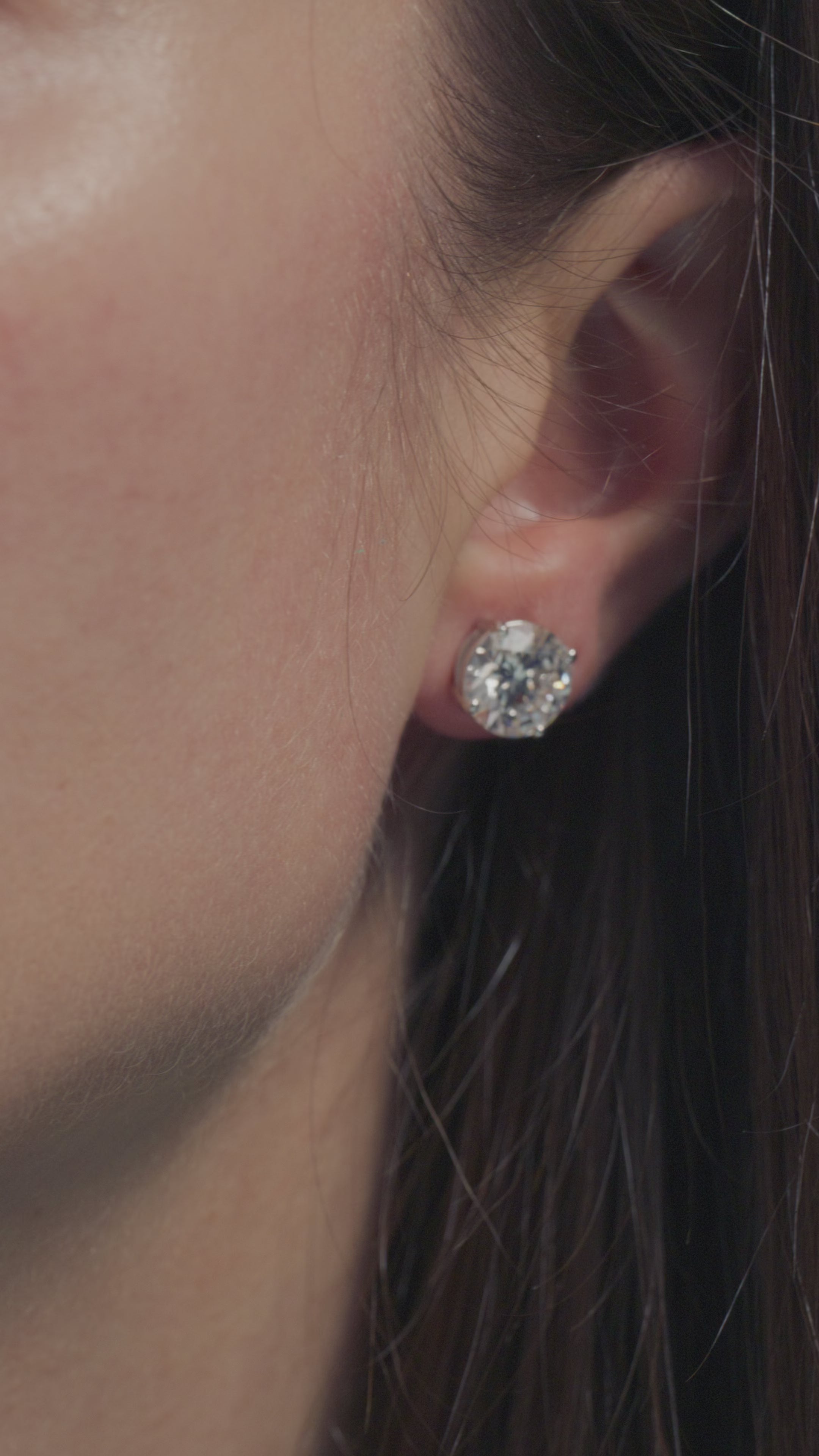 A video presentation of a 3ct Round Solitaire Earrings worn on the lobe of the model 