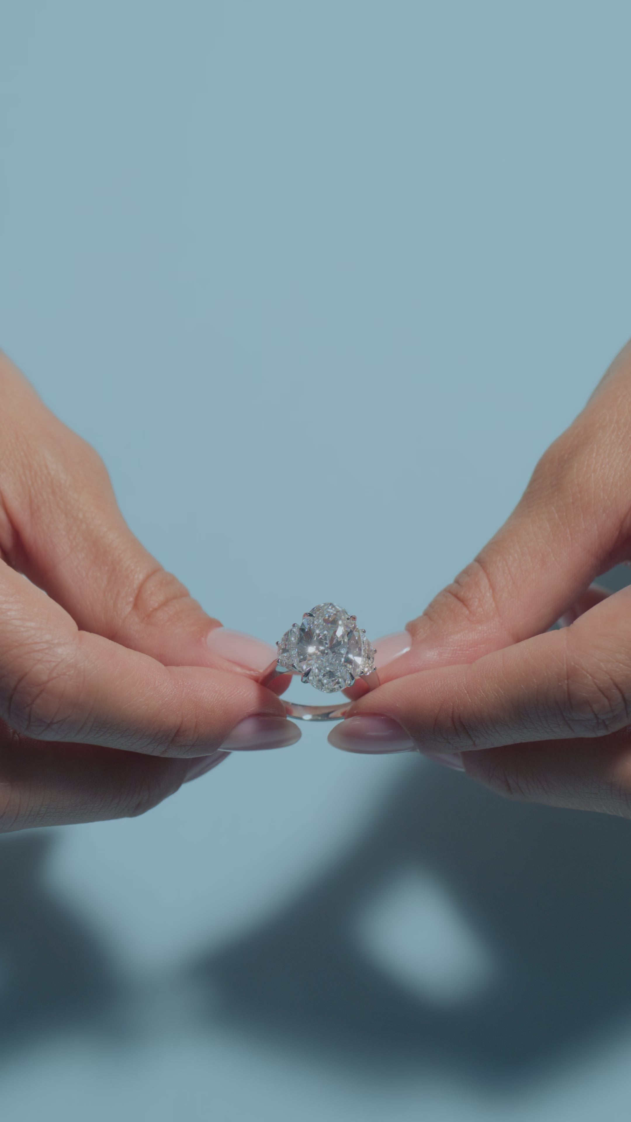 A short video of a 6.5ct Oval Lab Diamond Classic Trilogy Ring presented by the model of BAL Diamonds on a light blue background 