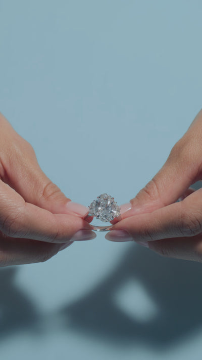 A short video of a 6.5ct Oval Lab Diamond Classic Trilogy Ring presented by the model of BAL Diamonds on a light blue background 