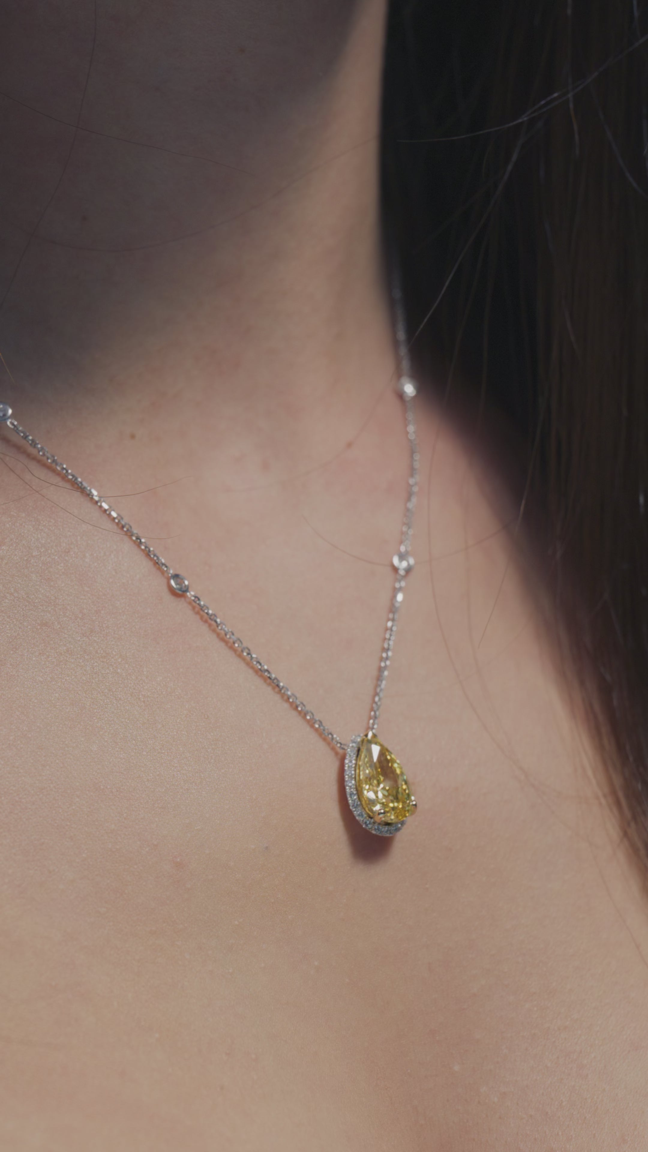 A video presentation of a 4.09ct pear-shaped Fancy Vivid Yellow lab diamond halo pendant, worn on the neck of a BAL Diamonds model.