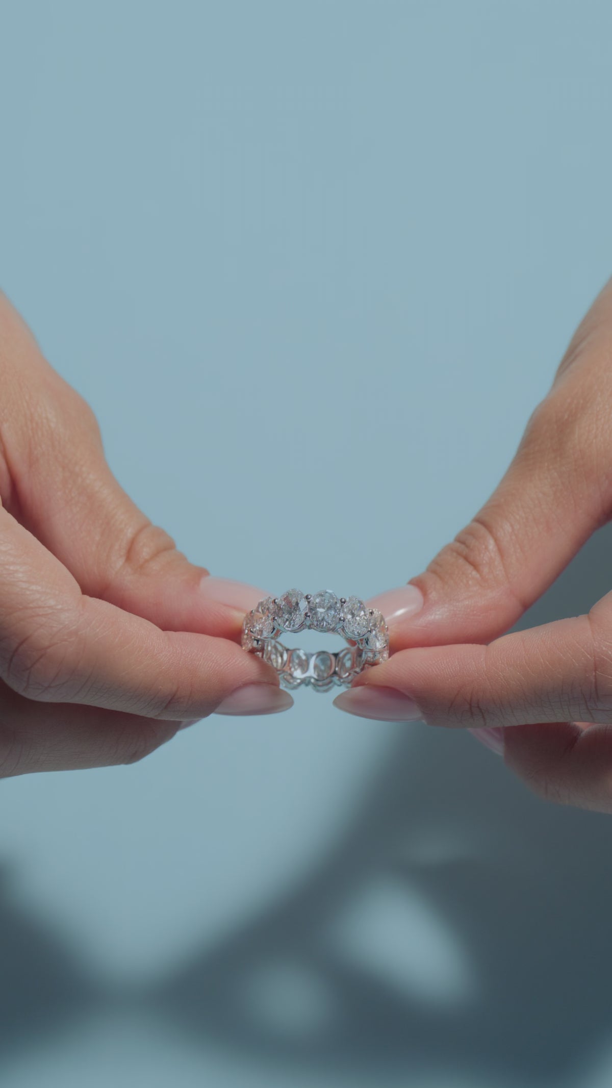 A video clip featuring a 10.59ct Oval Lab Diamonds Eternity Ring held and worn by the model on a light blue backround